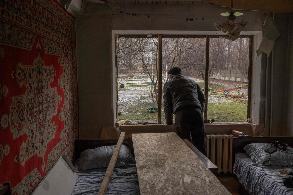 A man stands inside his damaged apartment following an overnight shelling in Myrnohrad, Donetsk region, on January 26, 2024, amid the Russian invasion of Ukraine. (Photo by Roman PILIPEY / AFP)