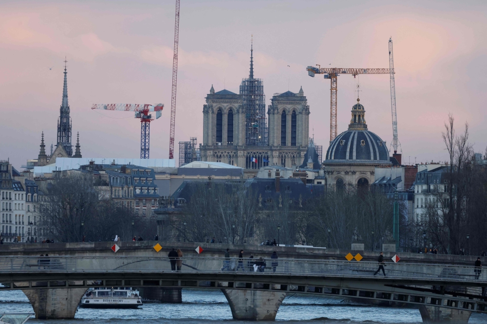 This photograph taken on February 12, 2024, shows illuminated construction site of Notre-Dame de Paris Cathedral with its rear spire, in Paris. (Photo by Ludovic MARIN / AFP)