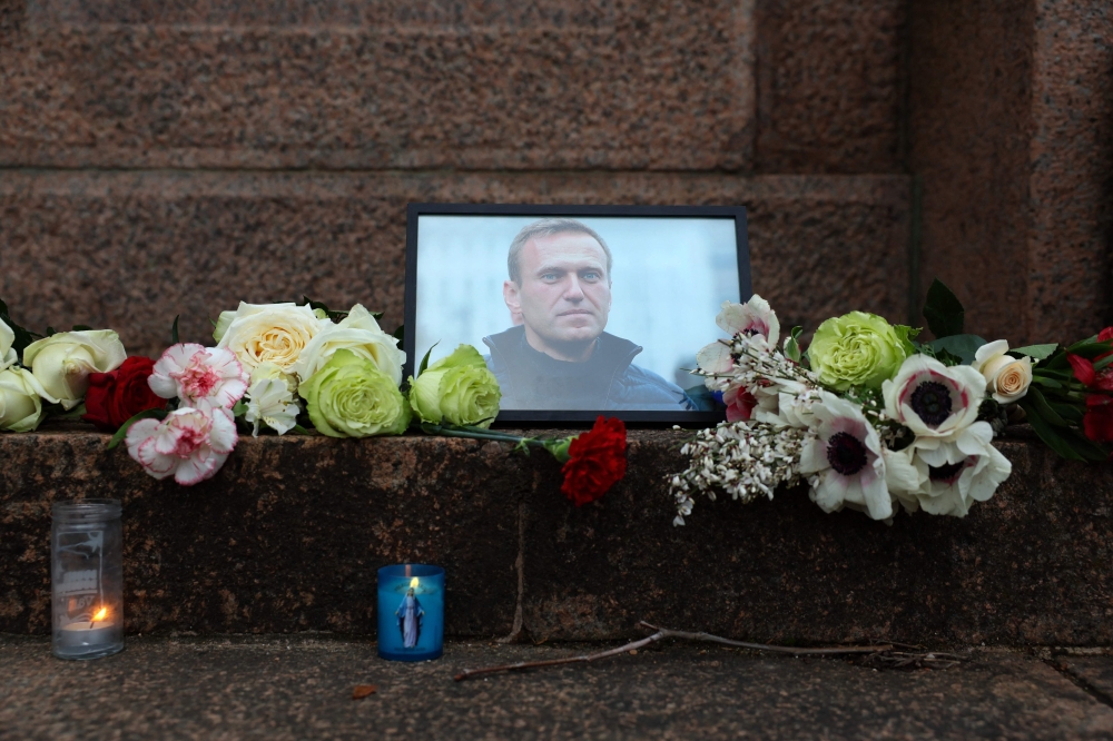 A portrait of Alexei Navalny, candles and flowers are left at a memorial in Paris on February 16, 2024, after the announcement that the Kremlin's most prominent critic had died in an Arctic prison. (Photo by Ian LANGSDON / AFP)

