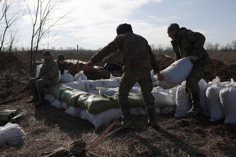 Ukrainian servicemen pile up earthbags to build a fortification not far from town of Avdiivka in the Donetsk region, amid the Russian invasion of Ukraine, on February 17, 2024. (Photo by Anatolii STEPANOV / AFP)