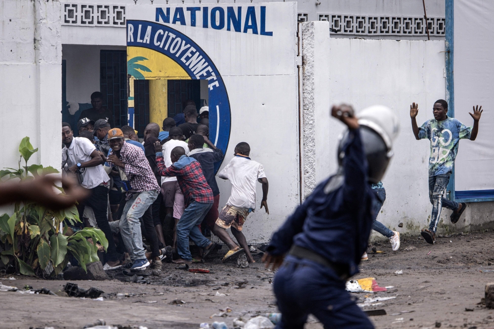 (File photo) A Police officer throws a rock as opposition supporters run into a opposition leader Martin Fayulu's party house during a demonstration in Kinshasa on December 27, 2023. (Photo by JOHN WESSELS / AFP)

