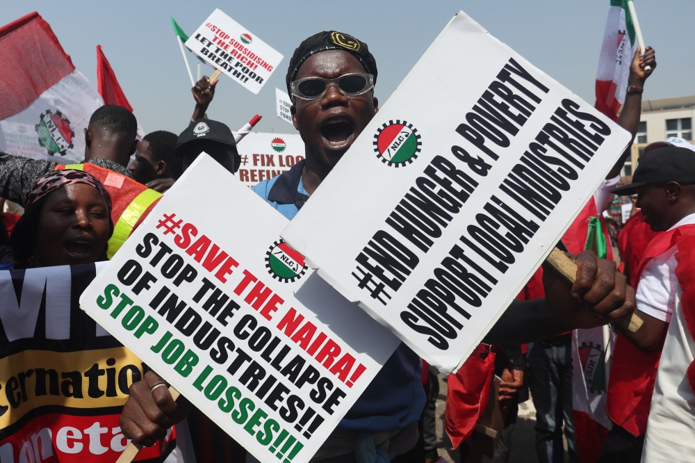 A protestor holds placards during a protest in Abuja on February 27, 2024. (Photo by Kola Sulaimon / AFP)
