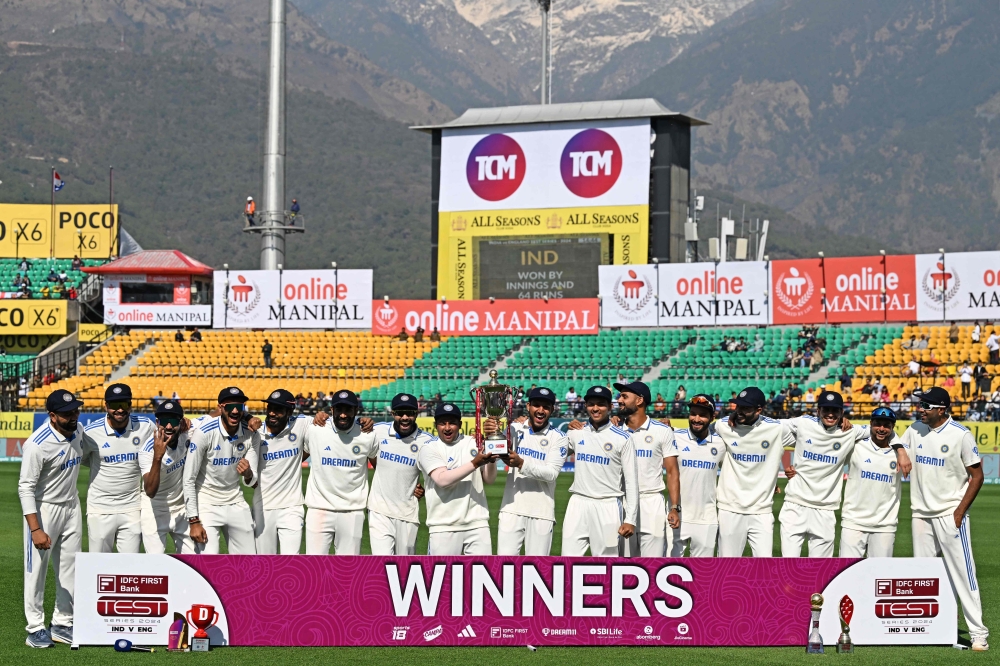 India's players pose with the trophy after winning the fifth and last Test cricket match between India and England at the Himachal Pradesh Cricket Association Stadium in Dharamsala on March 9, 2024. (Photo by Sajjad HUSSAIN / AFP)