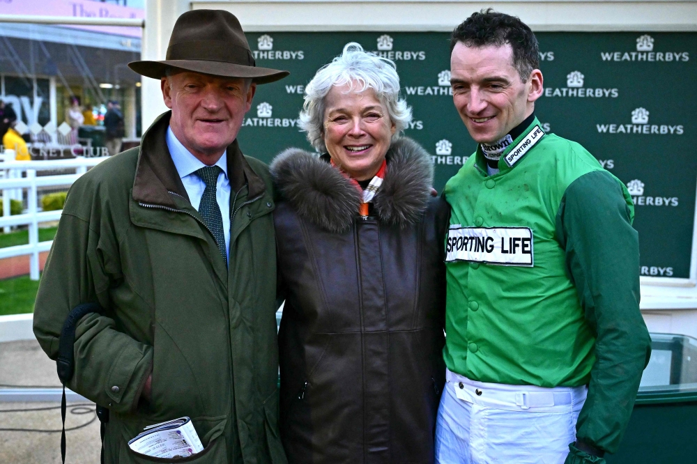 Trainer Willie Mullins (L) poses for a photograph with his wife Jackie and his son jockey Patrick Mullins, after his 100th win with Jasmin De Vaux winning the Champion Bumper race on the second day of the Cheltenham Festival at Cheltenham Racecourse, in Cheltenham, western England on March 13, 2024. (Photo by Ben Stansall / AFP)
