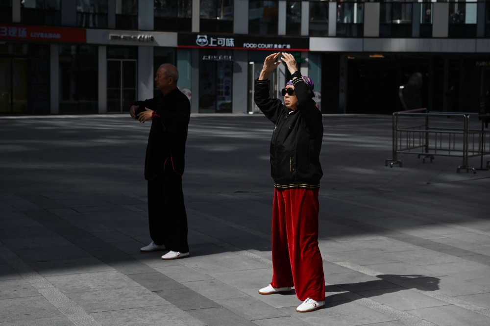 A man and woman perform martial arts exercises at a shopping mall in Beijing on March 17, 2024. (Photo by GREG BAKER / AFP)