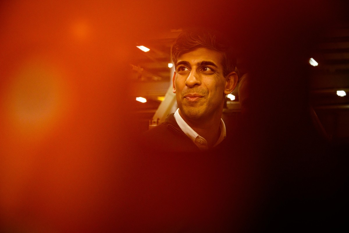 Britain's Prime Minister Rishi Sunak is pictured through a metal grill as he speaks with practical apprentices, during a visit to the Rolls-Royce manufacturing facility in Bristol on March 14, 2024. Photo by Leon Neal / POOL / AFP