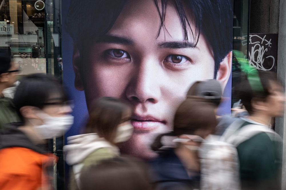 People walk past an advertisement with a picture of Shohei Ohtani in Tokyo on March 17, 2024. (Photo by Yuichi YAMAZAKI / AFP)