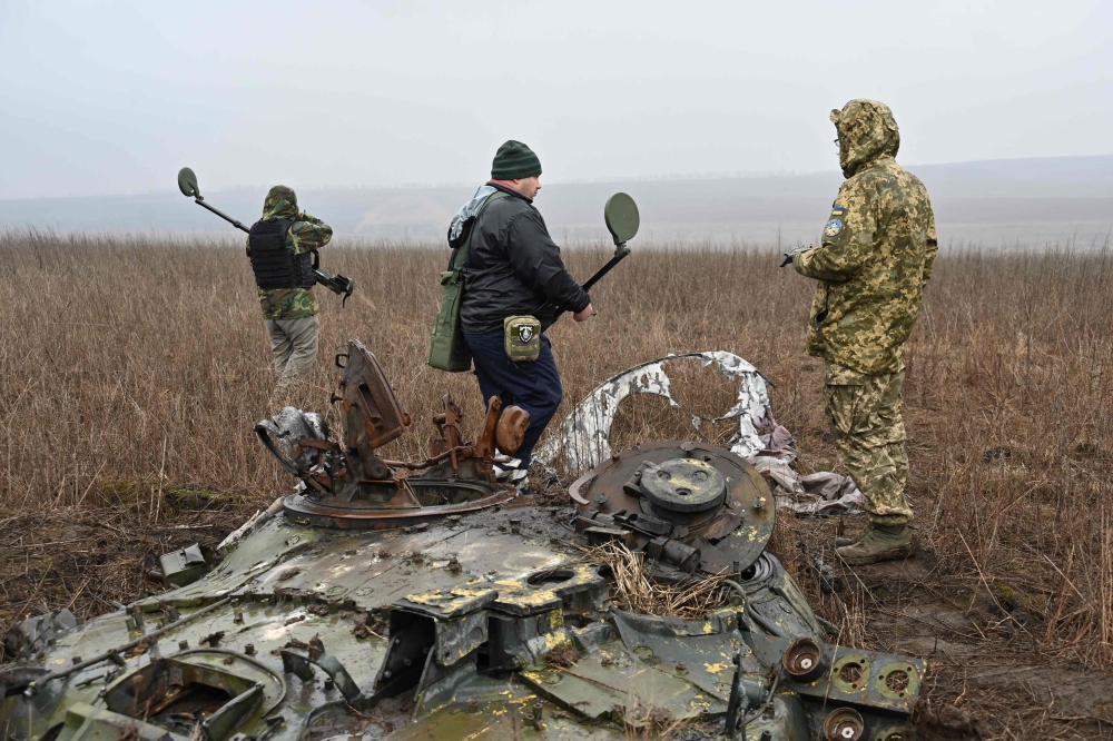Deminers of the charitable fund 'Demining of Ukraine' use metal detectors to search for mines in the field near the town of Derhachi, Kharkiv region, on March 19, 2024, amid the Russian invasion of Ukraine. Photo Credit: SERGEY BOBOK / AFP.