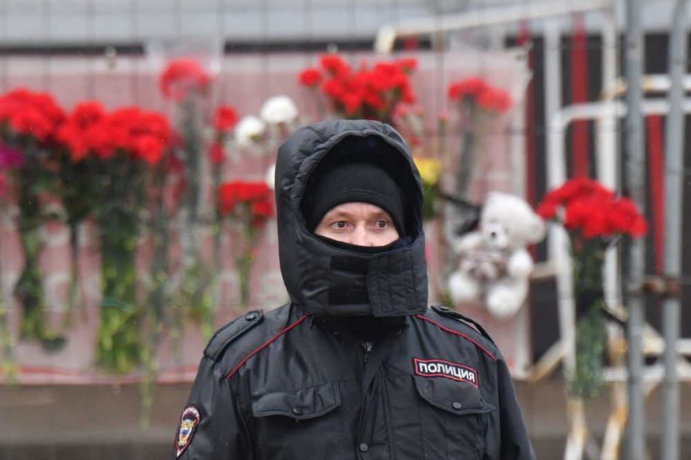 A police officer stands guard at a makeshift memorial in front of the Crocus City Hall, a day after a gun attack in Krasnogorsk, outside Moscow, on March 23, 2024. (Photo by Olga Maltseva / AFP)
 