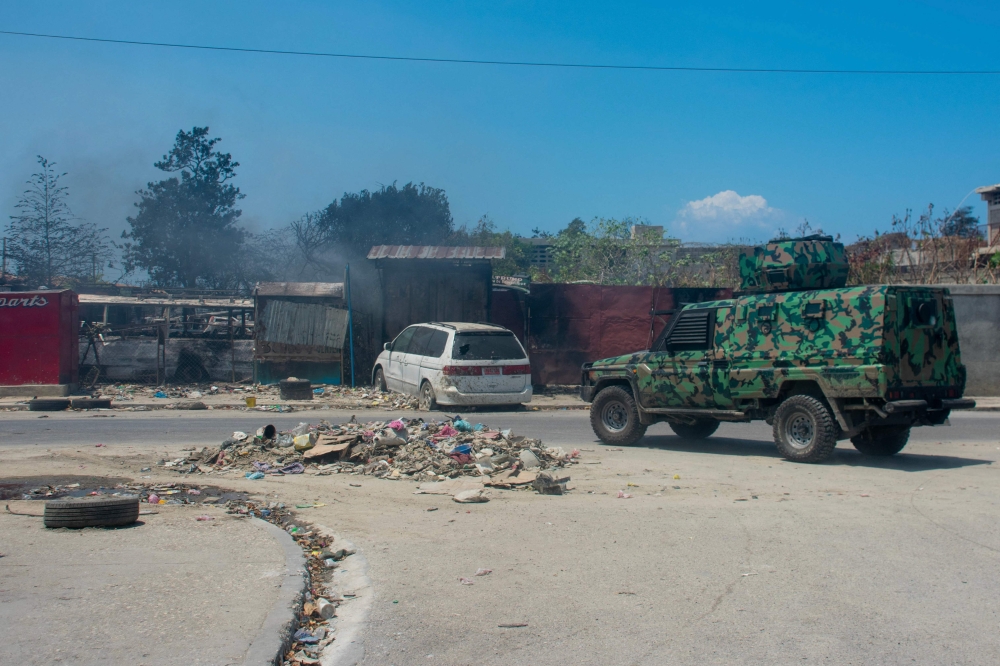 A police vehicle patrols an area that was set fire to by armed gangs in Port-au-Prince, Haiti, on March 25, 2024. (Photo by Clarens SIFFROY / AFP)
