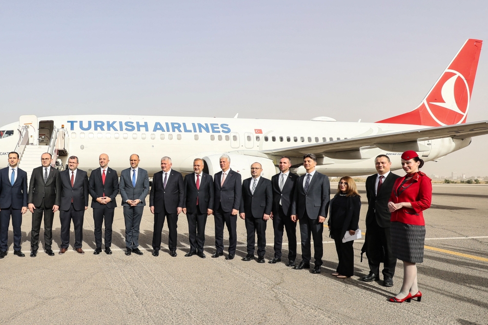 Libyan and Turkish officials pose in front of a Turkish Airlines air plane, following its first landing after a near 10-year hiatus, at the Mitiga International Airport in Tripoli on March 28, 2024. (Photo by Mahmud Turkia / AFP)