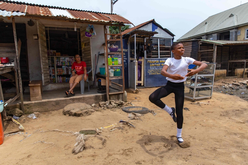 (FILES) A student of the Leap of Dance Academy, Anthony Madu (R), performs a ballet dance routine in front of his mother's shop in Okelola street in Ajangbadi, Lagos, on July 3, 2020. (Photo by Benson Ibeabuchi / AFP)
