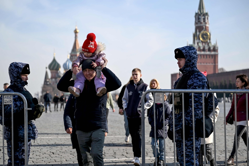 People walk past Russian law enforcement officers standing guard at the Red Square in Moscow on March 29, 2024. Photo by NATALIA KOLESNIKOVA / AFP.