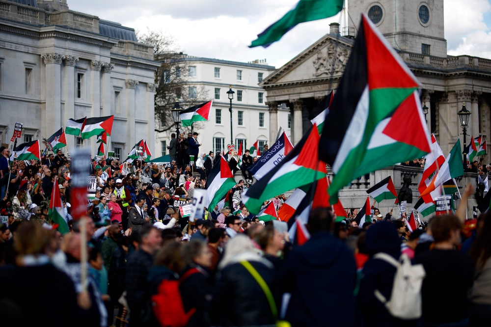 Pro-Palestinian activists and supporters wave flags as they gather for a protest in Trafalgar Square in central London on March 30, 2024, calling for a ceasefire in Gaza. (Photo by Benjamin Cremel / AFP)