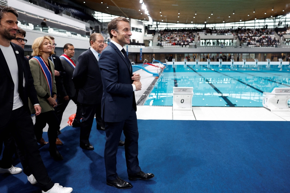 French President Emmanuel Macron, surrounded by Tony Estanguet, president of the Paris 2024 Olympics Organising Committee, Ile-de-France's Regional Council President Valerie Pecresse, Grand Paris' Metropole President Patrick Ollier and officials, visits the Olympic aquatics centre (CAO), a multifunctional venue for the Paris 2024 Olympics, on the day of its inauguration in Saint-Denis, outside Paris, on April 4, 2024. (Photo by Gonzalo Fuentes / POOL / AFP)