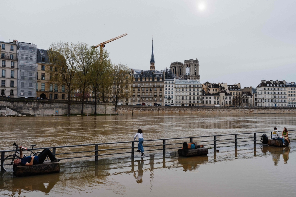 People enjoy the warm weather at the flooded docks along the Seine river in Paris on April 6, 2024. (Photo by Dimitar DILKOFF / AFP)