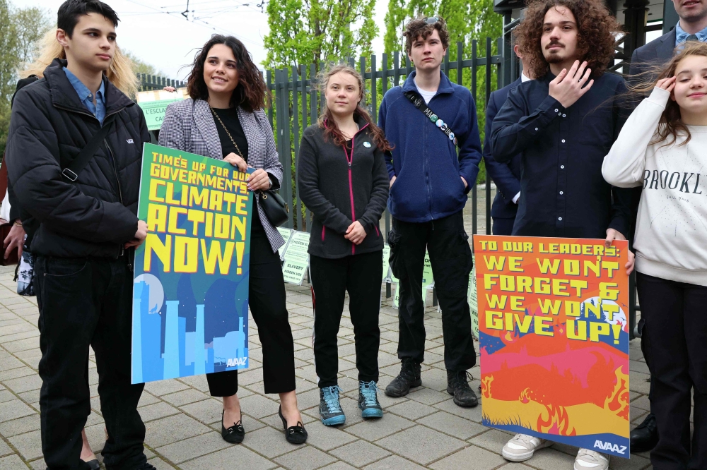 Swedish climate activist Greta Thunberg (C) and protesters hold placards during a rally before the European Court of Human Rights (ECHR) decides in three separate cases in Strasbourg, eastern France, on April 9, 2024. (Photo by Frederick Florin / AFP)