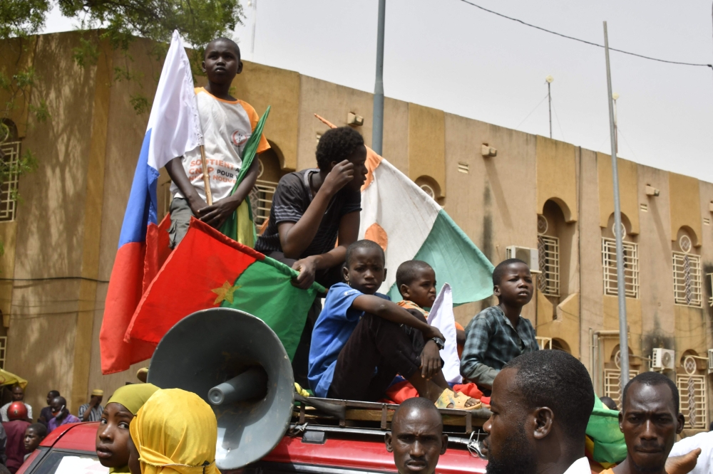 Young boys gather on top of a car while displaying flags of Niger, Burkina Faso and Russia during a demonstration for the immediate departure of United States Army soldiers deployed in northern Niger in Niamey, on April 13, 2024. (Photo by AFP)
