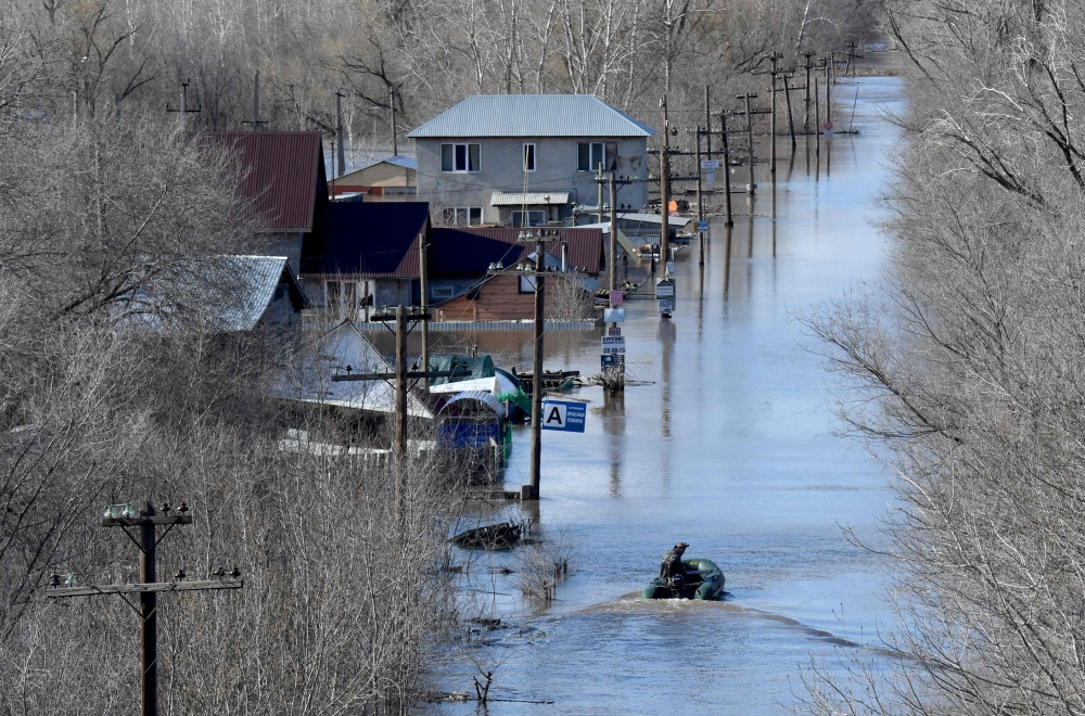 A resident sails a rubber boat in a flooded residential area in the city of Orenburg on April 13, 2024. (Photo by Olga MALTSEVA / AFP)
