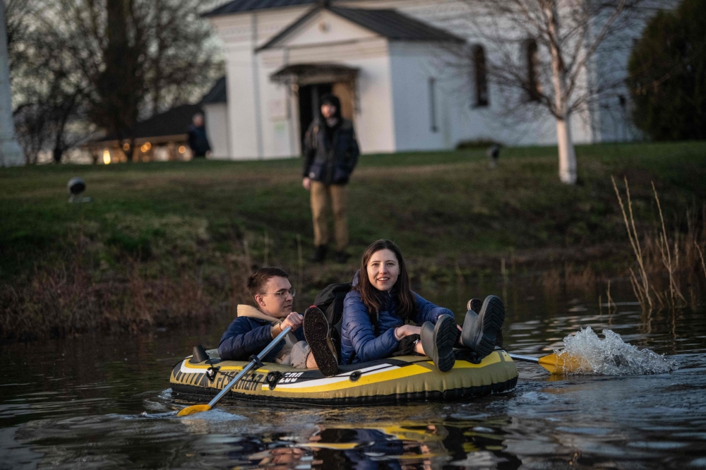 People travel in a boat in floodwater from the overflowing Nerl River in front of the Church of the Intercession on the Nerl off the settlement of Bogolyubovo in the Vladimir region on April 13, 2024. Photo by Valery MELNIKOV / AFP.
