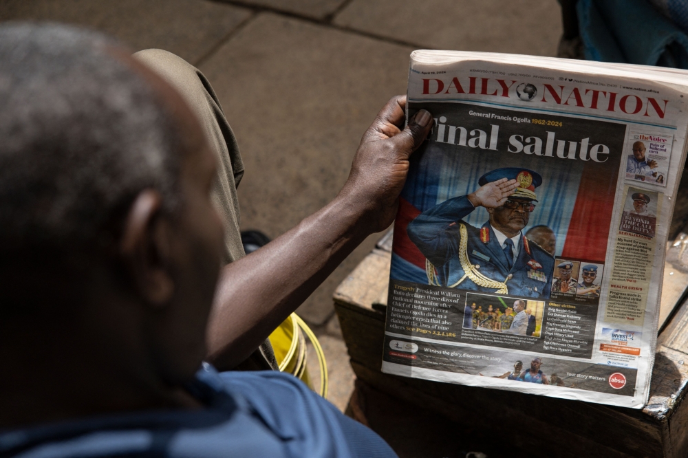 A man looks at a newspaper with the headline of the death of defence chief General Francis Omondi Ogolla and nine other senior military officers who were killed in a helicopter crash, in Nairobi on April 19, 2024. Photo by SIMON MAINA / AFP