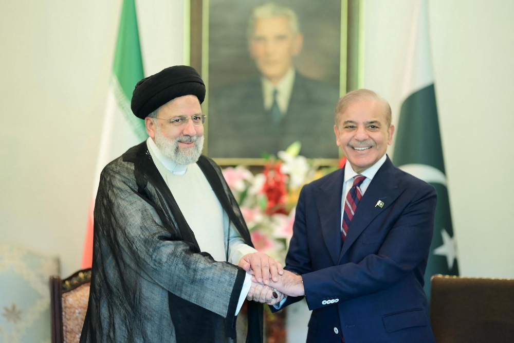 This handout photograph taken on April 22, 2024, and released by Pakistan's Press Information Department (PID) shows Iran痴 President Ebrahim Raisi (L) shakes hands with Pakistan's Prime Minister Shehbaz Sharif upon his arrival at the Prime Minister House in Islamabad. (Photo by Pakistan Press Information Department (PID) / AFP)
