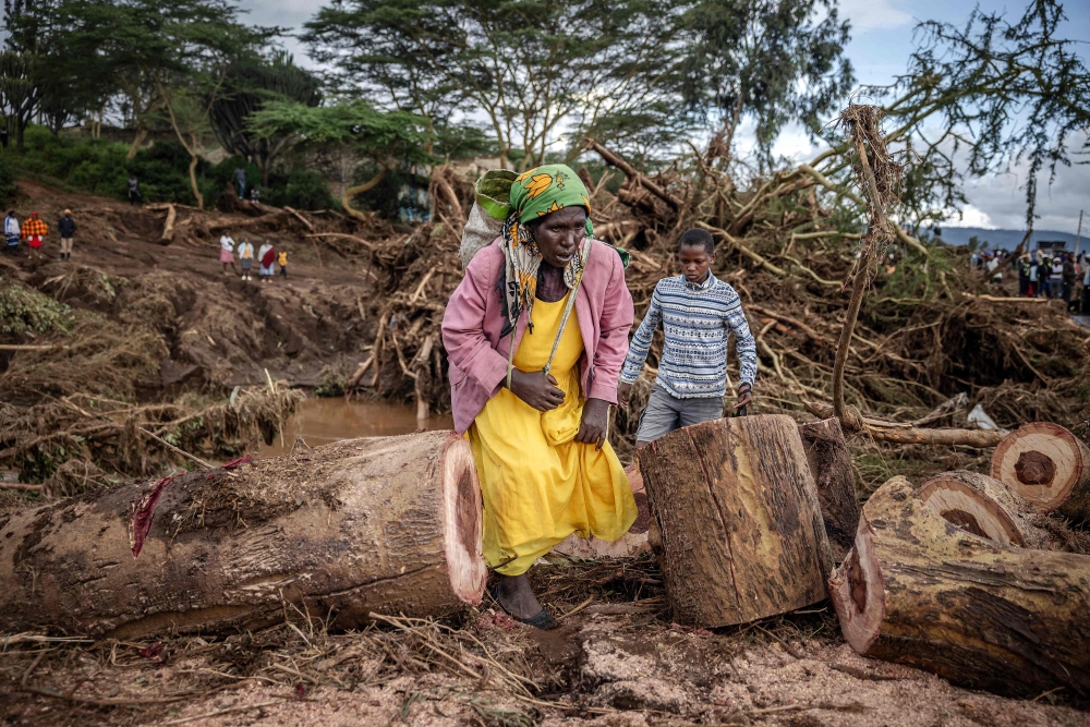  A woman walks in an area full of damaged trees, mud and debris carried by water following flash floods and landslides in Mai Mahiu, on April 30, 2024. Photo by LUIS TATO / AFP