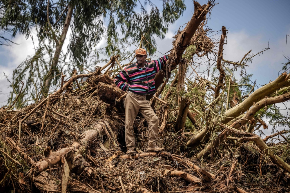 A man looks on while standing on top of a pile of debris in an area full of damaged trees and mud carried by water following flash floods and landslides in Mai Mahiu, on April 30, 2024. (Photo by LUIS TATO / AFP)
