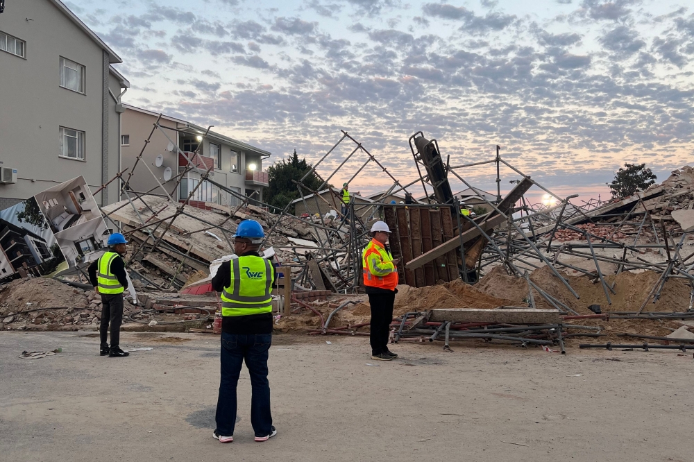 Officials are seen at the scene of a collapsed building in George on May 7, 2024. (Photo by Willie van Tonder / AFP)

