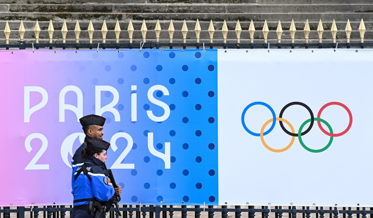 French Gendarmes walk past a banner for the forthcoming Paris 2024 Olympic Games outside The National Assembly - Assemblee nationale in Paris on May 5, 2024. (Photo by Stefano RELLANDINI / AFP)