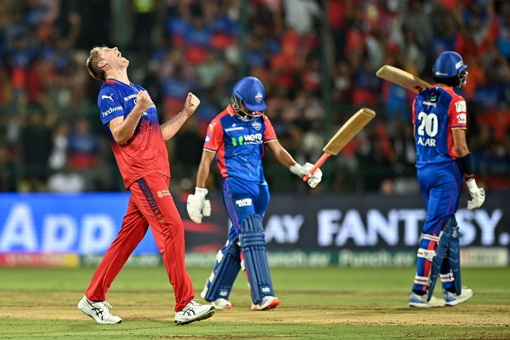 Royal Challengers Bengaluru's Cameron Green (L) celebrates after taking the wicket of Delhi Capitals' Rasikh Salam (C) during the Indian Premier League (IPL) Twenty20 cricket match between Royal Challengers Bengaluru and Delhi Capitals at the M Chinnaswamy Stadium in Bengaluru on May 12, 2024. (Photo by Idrees MOHAMMED / AFP)