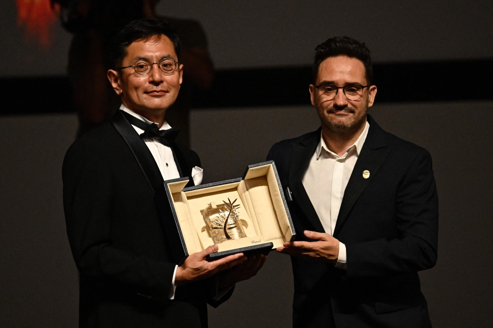 Japanese director and Ghibli Park Creative Development manager Goro Miyazaki is awarded with the Honorary Palme by Spanish director, producer, and writer and member of the Jury of the 77th Cannes Film Festival Juan Antonio Bayona during the 77th edition of the Cannes Film Festival in Cannes, southern France, on May 20, 2024. Photo by LOIC VENANCE / AFP.