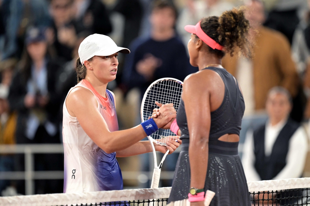 Poland's Iga Swiatek (left) shakes hands with Japan's Naomi Osaka after winning their women's singles match on Court Philippe-Chatrier on day four of the French Open tennis tournament at the Roland Garros Complex in Paris on May 29, 2024. (Photo by Bertrand Guay / AFP)