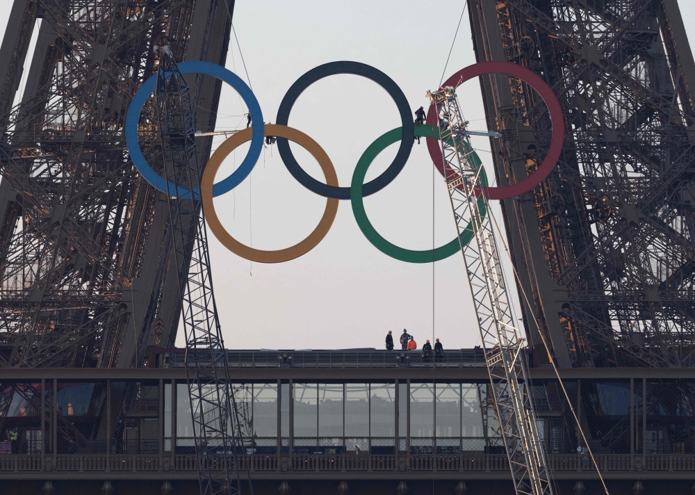 The Olympic rings are seen on the Eiffel Tower before an unveiling ceremony in Paris, early on June 7, 2024, ahead the upcoming Paris 2024 Olympic Games. (Photo by JOEL SAGET / AFP)