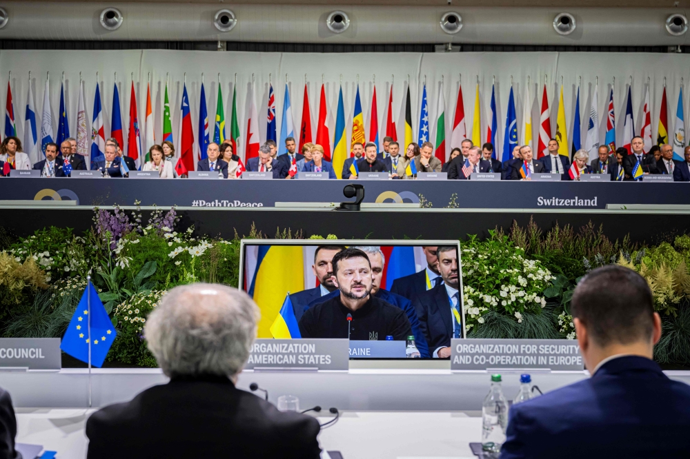 Ukraine's President Volodymyr Zelensky is seen on a screen during a plenary session at the Summit on peace in Ukraine, at the luxury Burgenstock resort, near Lucerne, on June 16, 2024.  (Photo by Urs Flueeler / POOL / AFP)