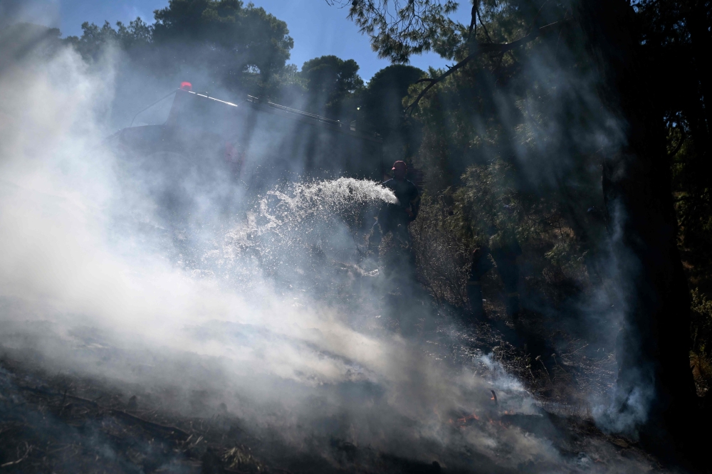 A firefighter works to extinguish a wildfire in Keratea, near Athens, on June 30, 2024. (Photo by Aris MESSINIS / AFP)
