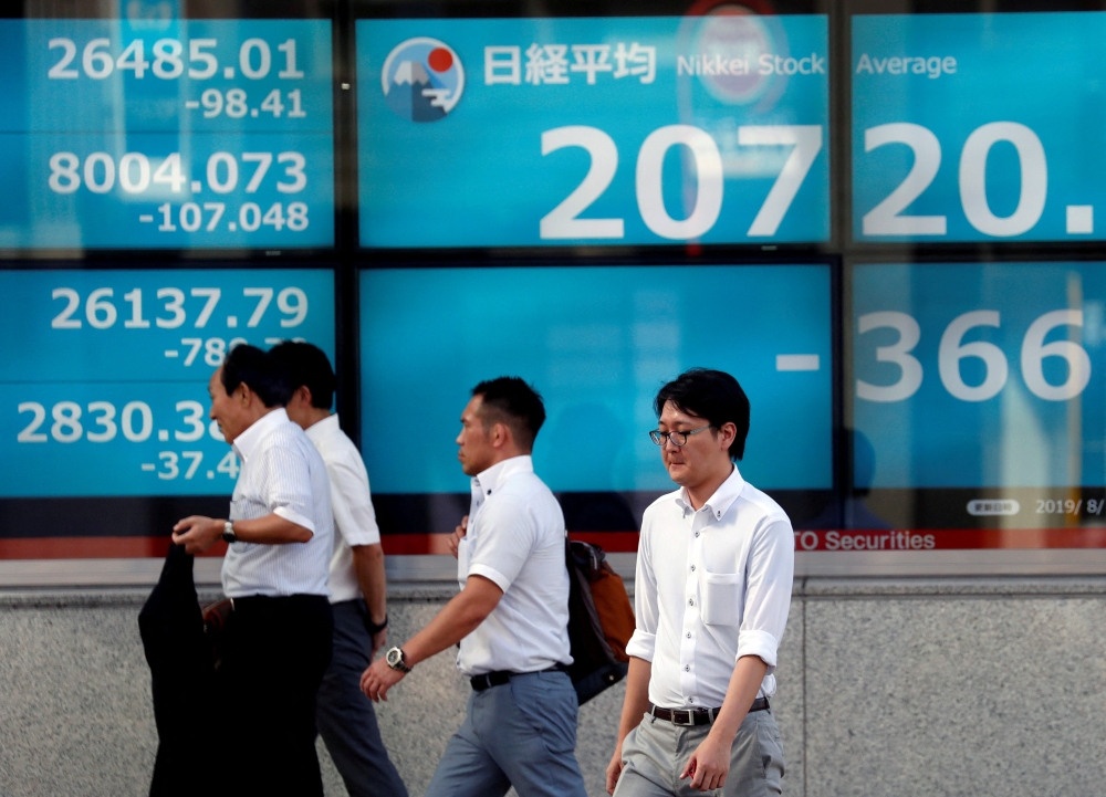 File photo: Men walk past in front of an electric screen showing Japan's Nikkei share average outside a brokerage in Tokyo, Japan, August 5, 2019. File Photo: REUTERS/Issei Kato

