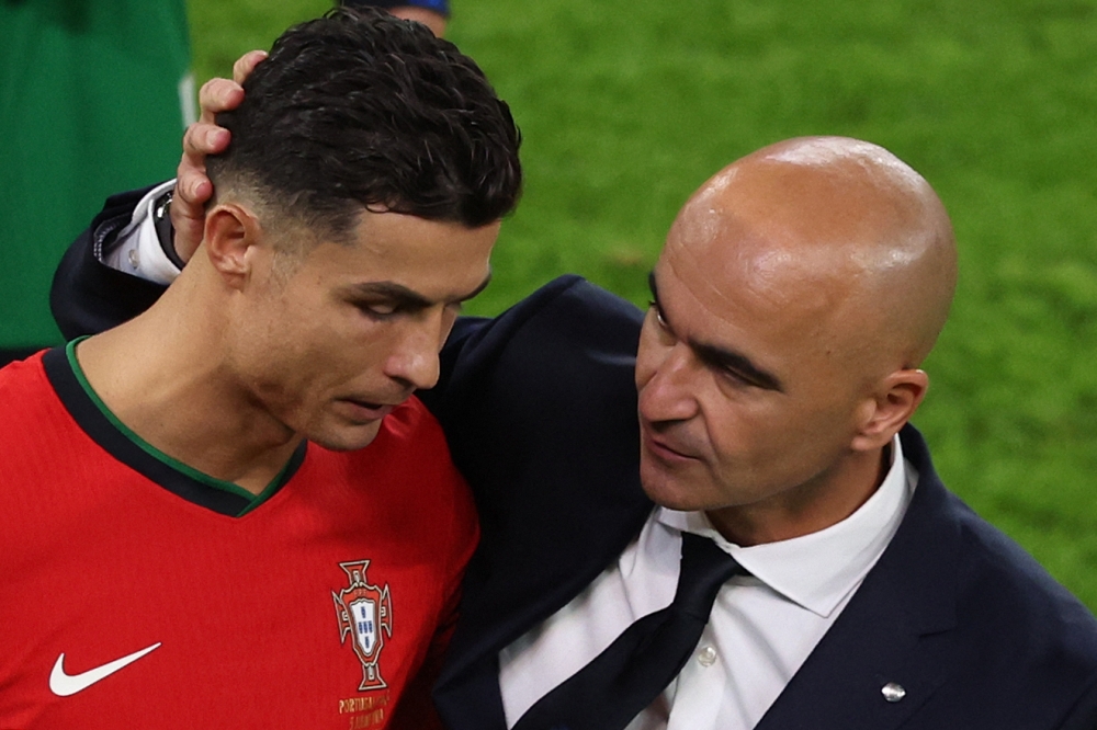 Portugal's forward Cristiano Ronaldo and head coach Roberto Martinez react at the end of the UEFA Euro 2024 quarter-final on July 5, 2024. (Photo by Ronny Hartmann / AFP)