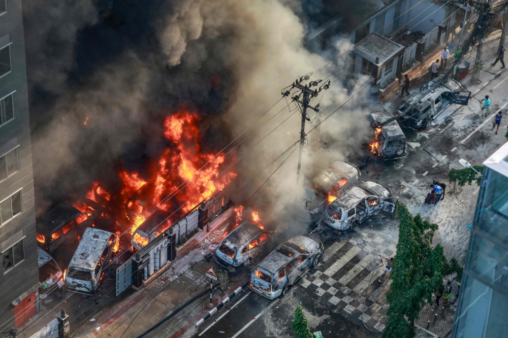 Smoke rises from the burning vehicles after protesters set them on fire near the Disaster Management Directorate office, during the ongoing anti-quota protest in Dhaka on July 18, 2024. (Photo by AFP)