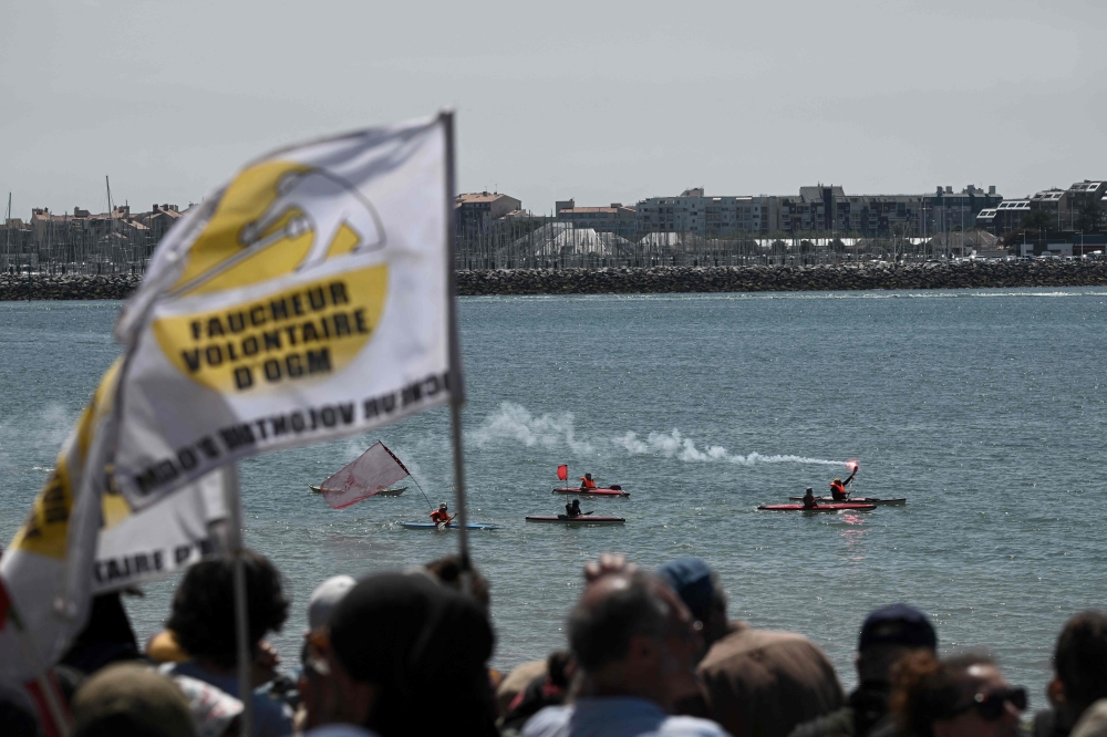 Protestors light a flare as they go in canoes off the coast, during a demonstration against the construction of giant water reservoir (mega-bassine) in La Rochelle, western France, on July 20, 2024. (Photo by Philippe Lopez / AFP)