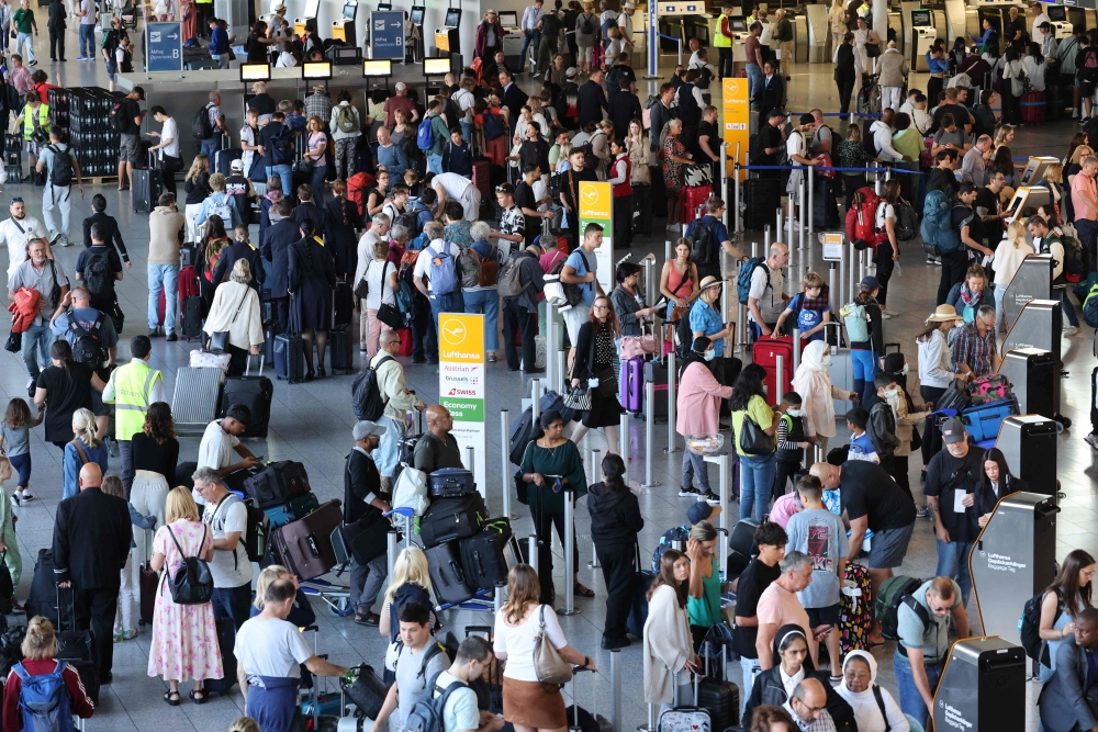 This picture taken on July 25, 2024, shows passengers queuing at the departures hall at Frankfurt's International Airport, western Germany. (Photo by Daniel ROLAND / AFP)