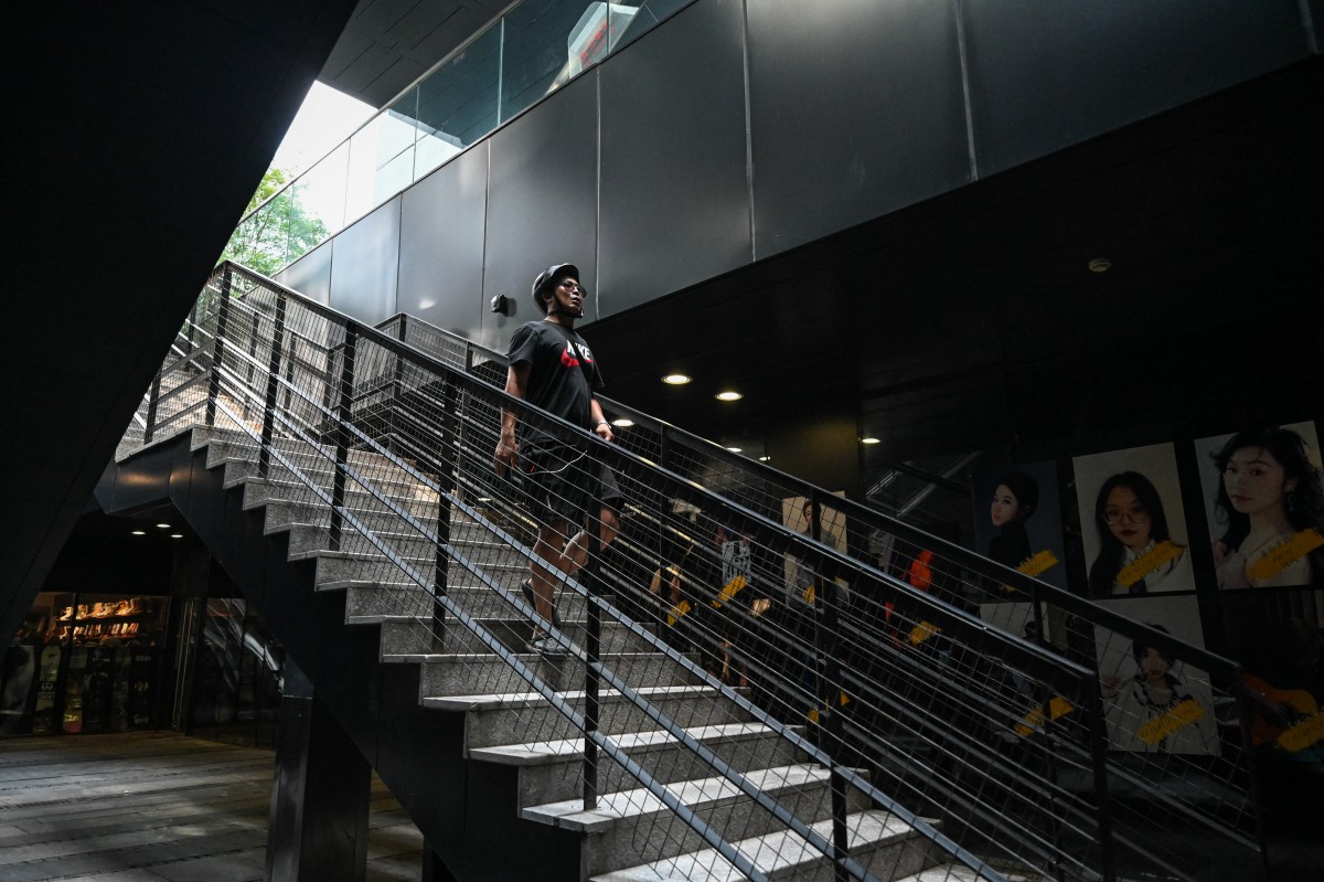 A man walks downstairs at an office building in Beijing on August 1, 2024. (Photo by JADE GAO / AFP)
