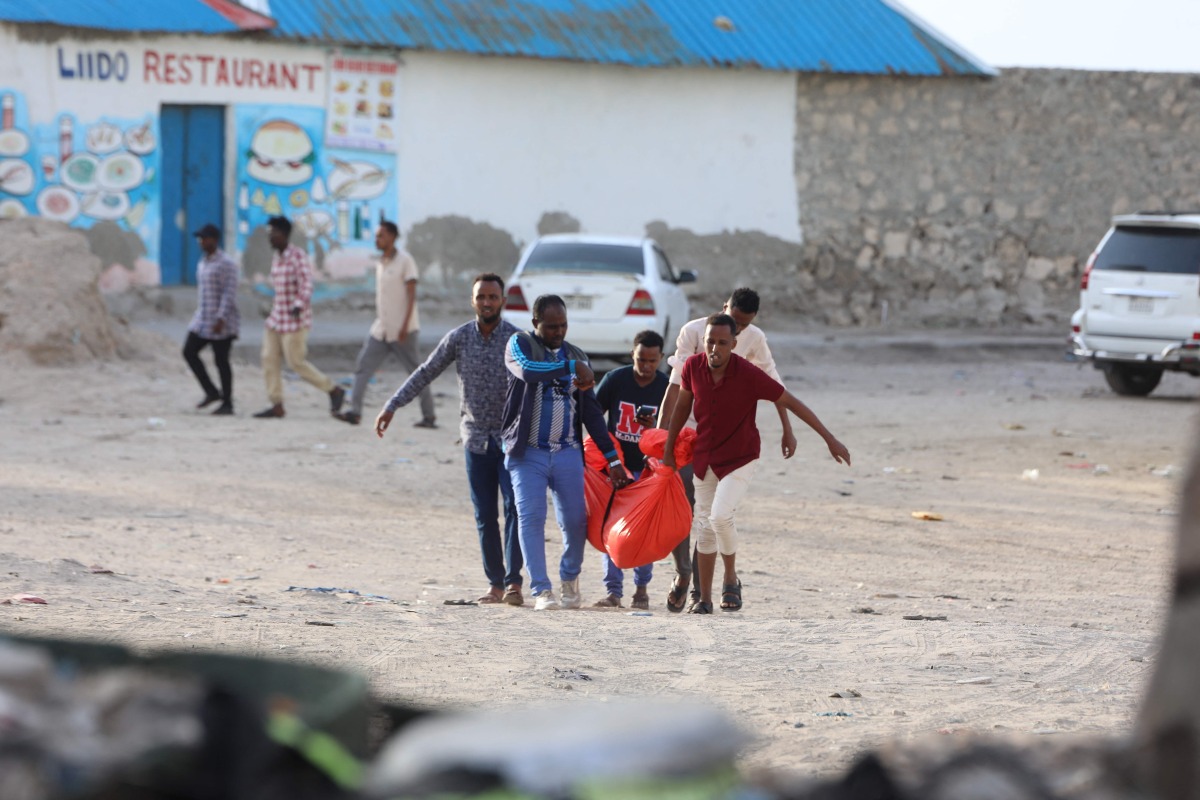 Relatives carry the body of a woman killed during an attack in Mogadishu on August 3, 2024. (Photo by Hassan Ali ELMI / AFP)
