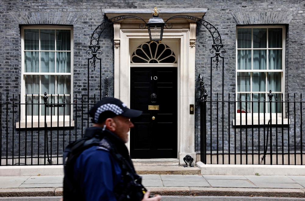 A police officer passes the door to 10 Downing Street, the official residence of Britain's Prime Minister, in central London on August 5, 2024. (Photo by BENJAMIN CREMEL / AFP)
