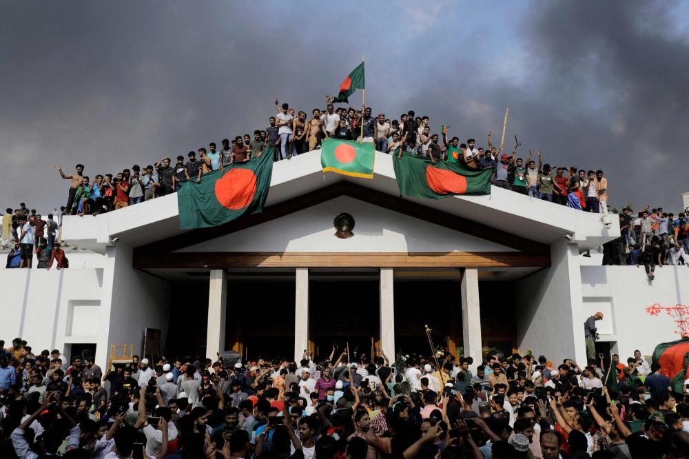 Anti-government protestors display Bangladesh's national flag as they storm Prime Minister Sheikh Hasina's palace in Dhaka on August 5, 2024. Photo by K M ASAD / AFP