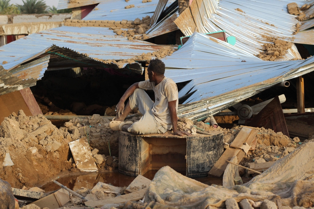 A Sudanese man sits amid the destruction in his village near the northern Sudanese town of Dongola on August 11, 2024 as floodwaters devastated the region disrupting transport, destroying houses and rendering thousands of people homeless. (Photo by AFP)