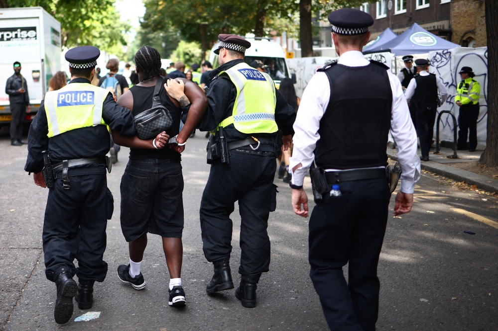 Police officers make an arrest at the Notting Hill Carnival in west London on August 26, 2024. (Photo by HENRY NICHOLLS / AFP)