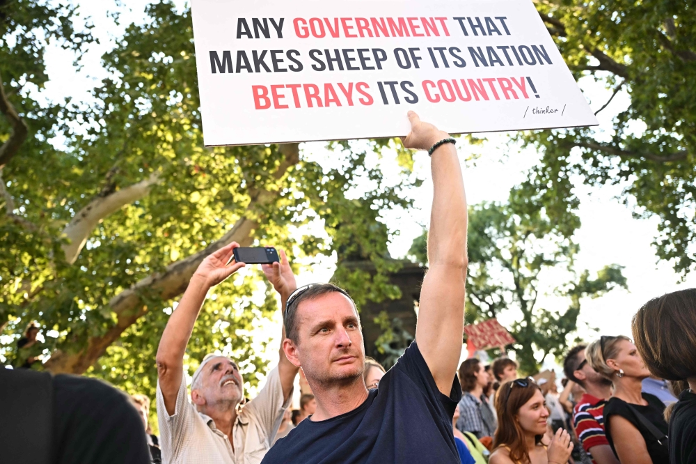 A demonstrator holds a banner as teachers, students and their sympathisers protest in central Budapest at the headquarters of the Interior Ministry on September 2, 2024, after the head of the renowned Madach Imre high school was sacked last week for not implementing a government-mandated 