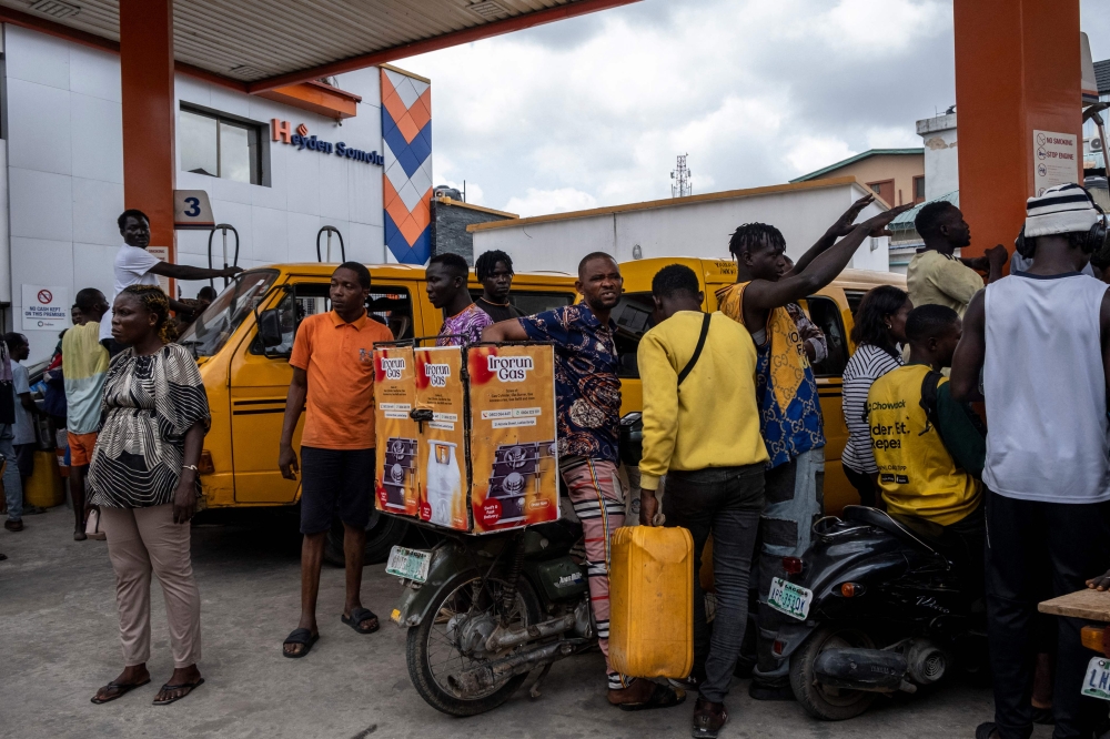 People wait to refill their jerrycans and fuel tanks at a fuel station in Lagos on September 4, 2024. (Photo by FAWAZ OYEDEJI / AFP)

