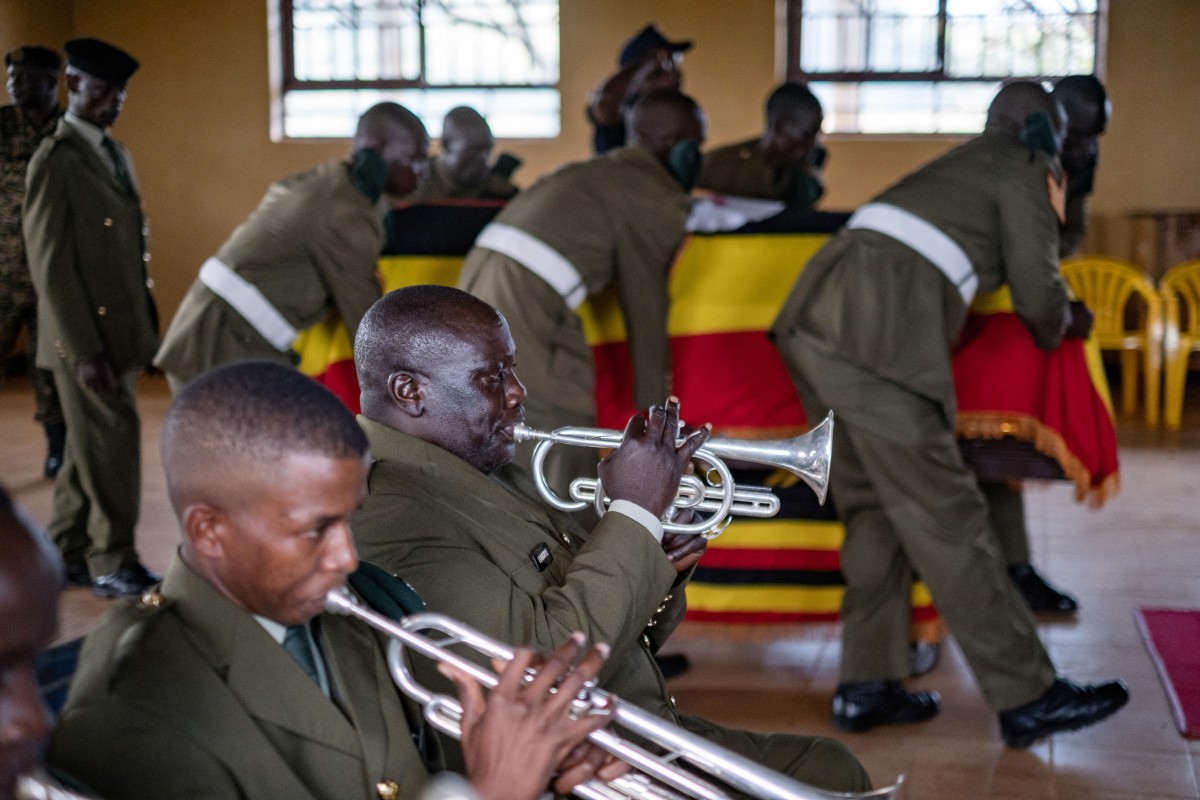 Uganda People's Defense Forces (UPDF) officers play musical instruments and place the coffin of Ugandan marathon runner Rebecca Cheptegei, 33, in the middle of the common room for people to pay their respects and mourn her in the district headquarters of the village of Bukwo on September 14, 2024. Photo by BADRU KATUMBA / AFP.